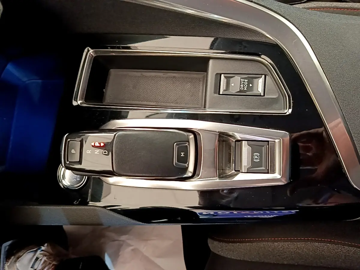 Vue rapprochée de la console centrale noire brillante du Peugeot 5008 2021, avec levier de vitesse automatique et bouton Drive Mode.
