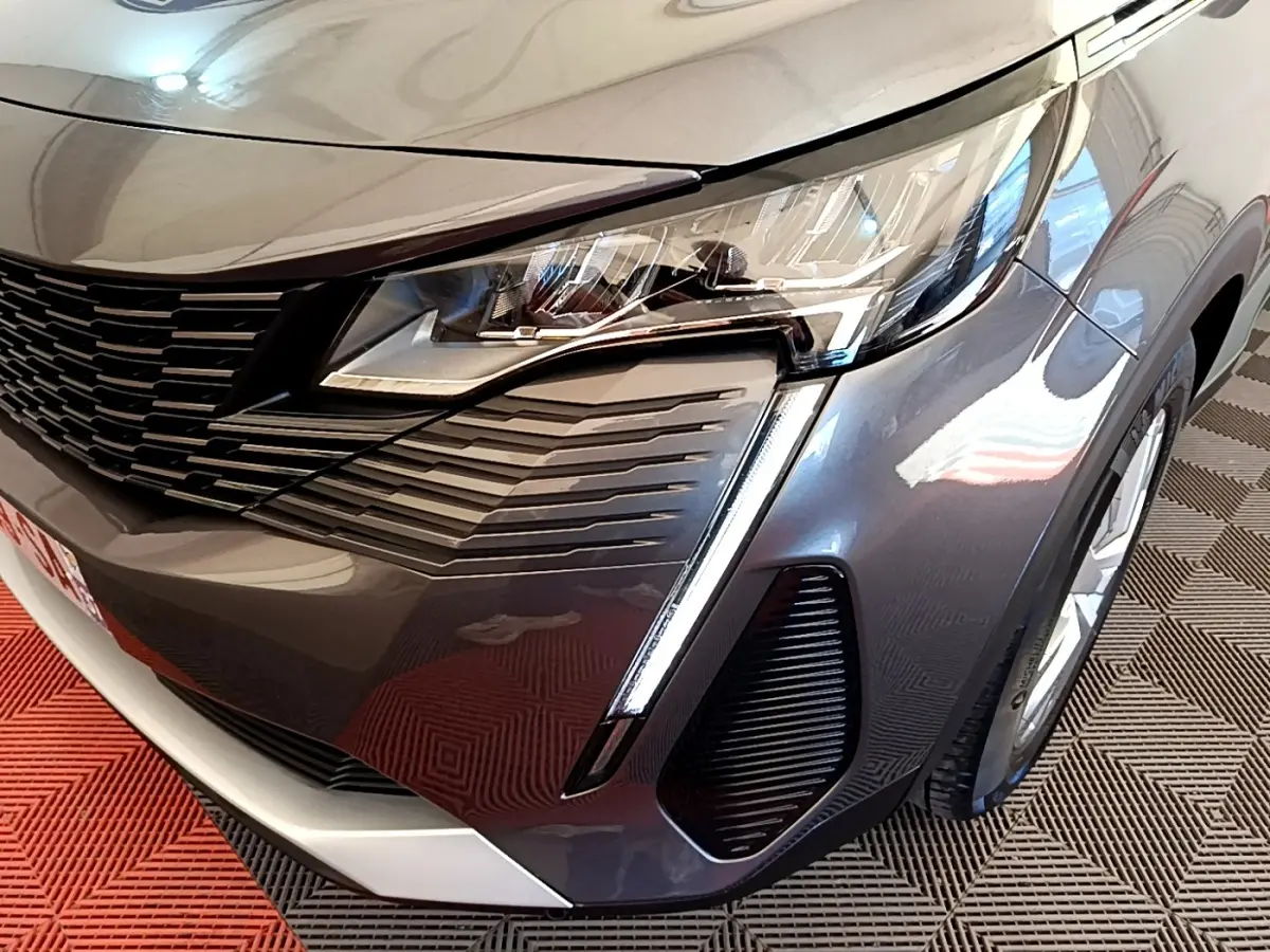 Gros plan sur l’avant droit gris clair du Peugeot 5008 2021 avec phares LED et calandre noire distinctive.