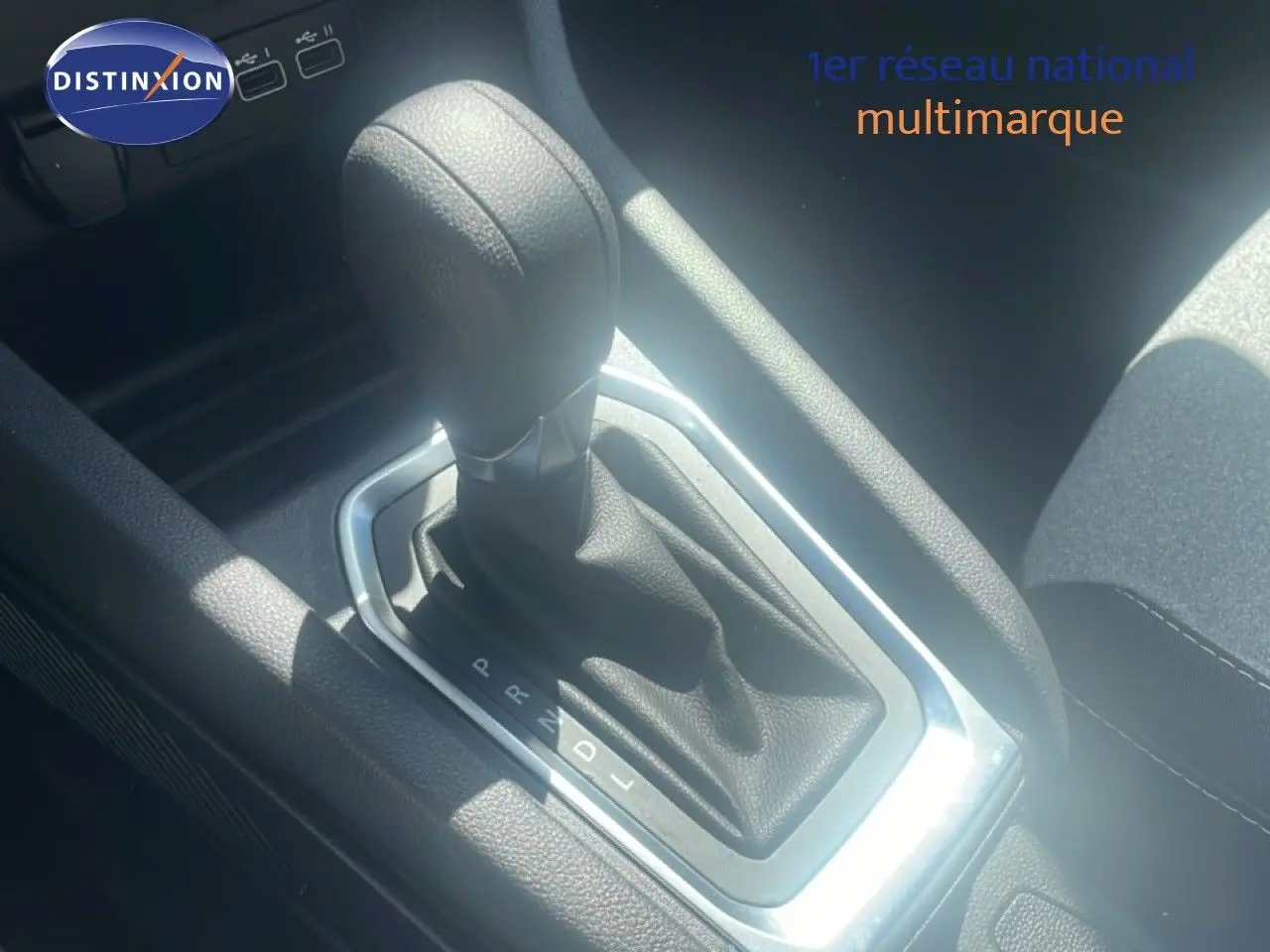 Gros plan sur le levier de vitesse automatique noir de la Renault Clio blanche 2025, intérieur tissu noir.