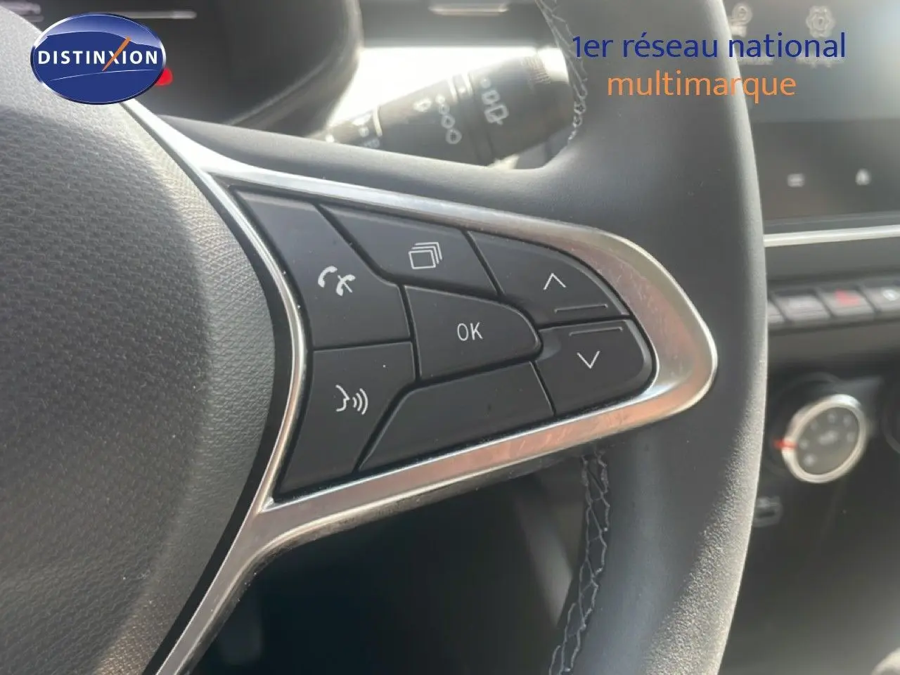 Gros plan sur les commandes multifonctions à droite du volant noir de la Renault Clio blanche, avec finition chromée.