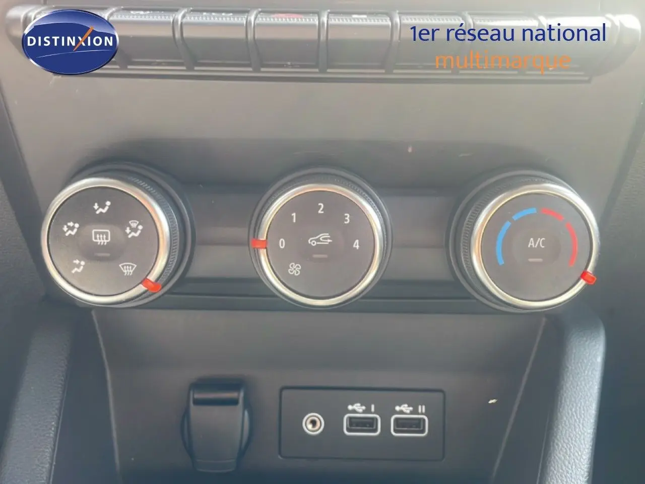 Gros plan sur les commandes de climatisation et les ports USB du tableau de bord d’une Renault Clio blanche 2025.