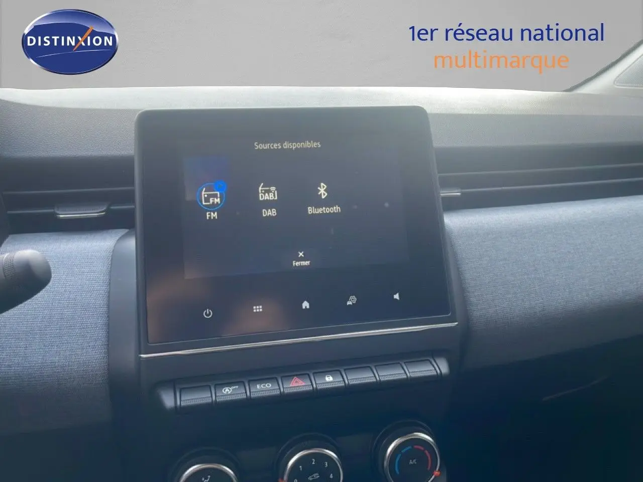 Vue rapprochée de l’écran tactile central et de la console de la Renault Clio blanche, avec commandes climatisation visibles.