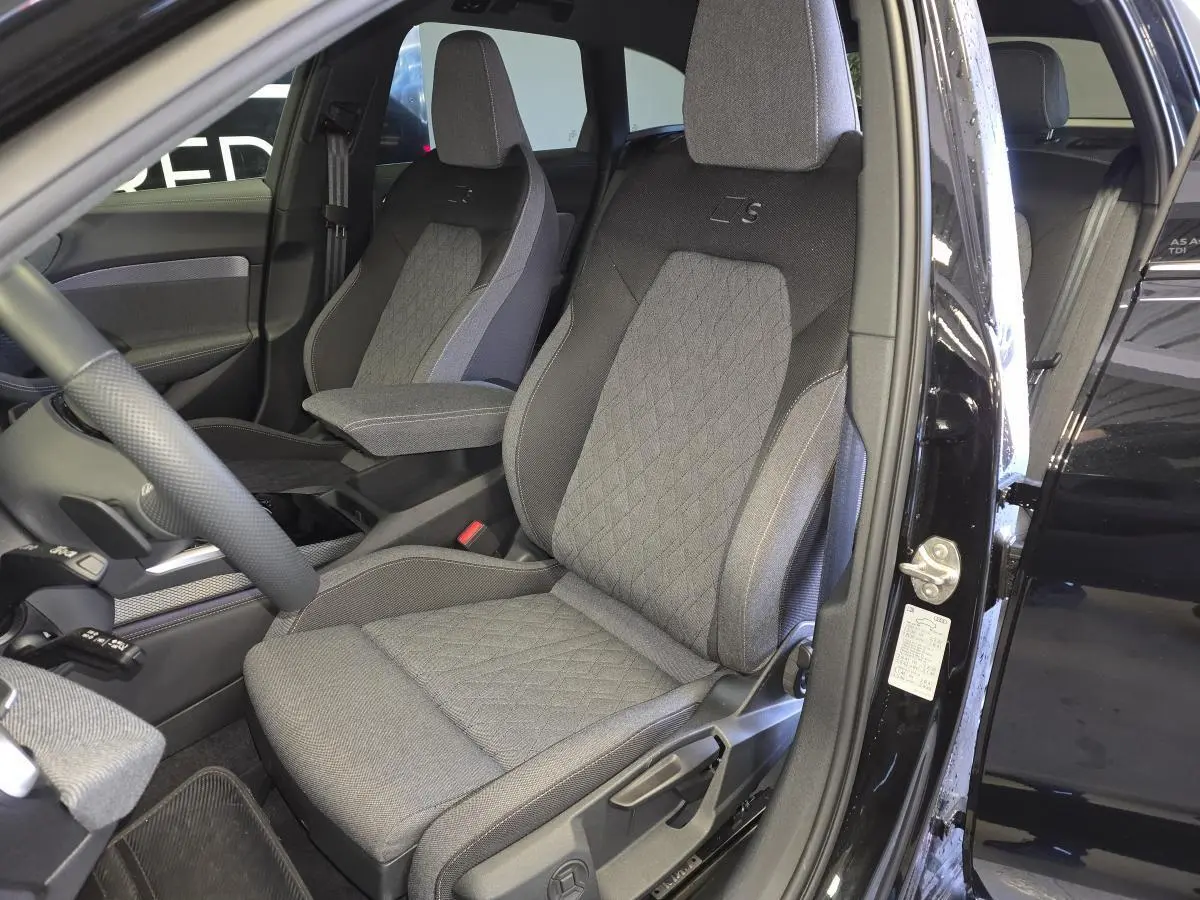 Vue intérieure côté conducteur de l'Audi A5 Avant noire, sièges sport tissu gris avec logo S brodé.