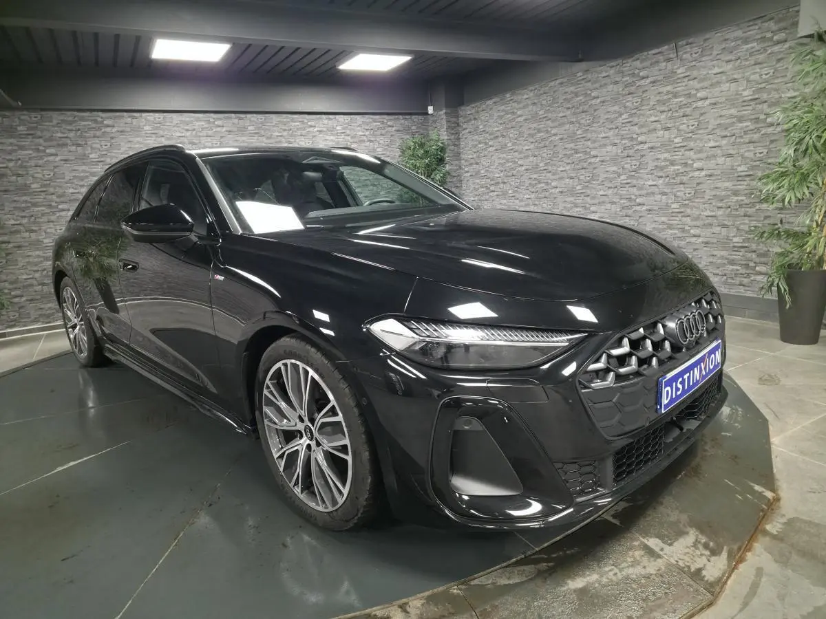 Audi A5 Avant S line noire vue 3/4 avant droit avec jantes 19 pouces et calandre hexagonale distinctive.