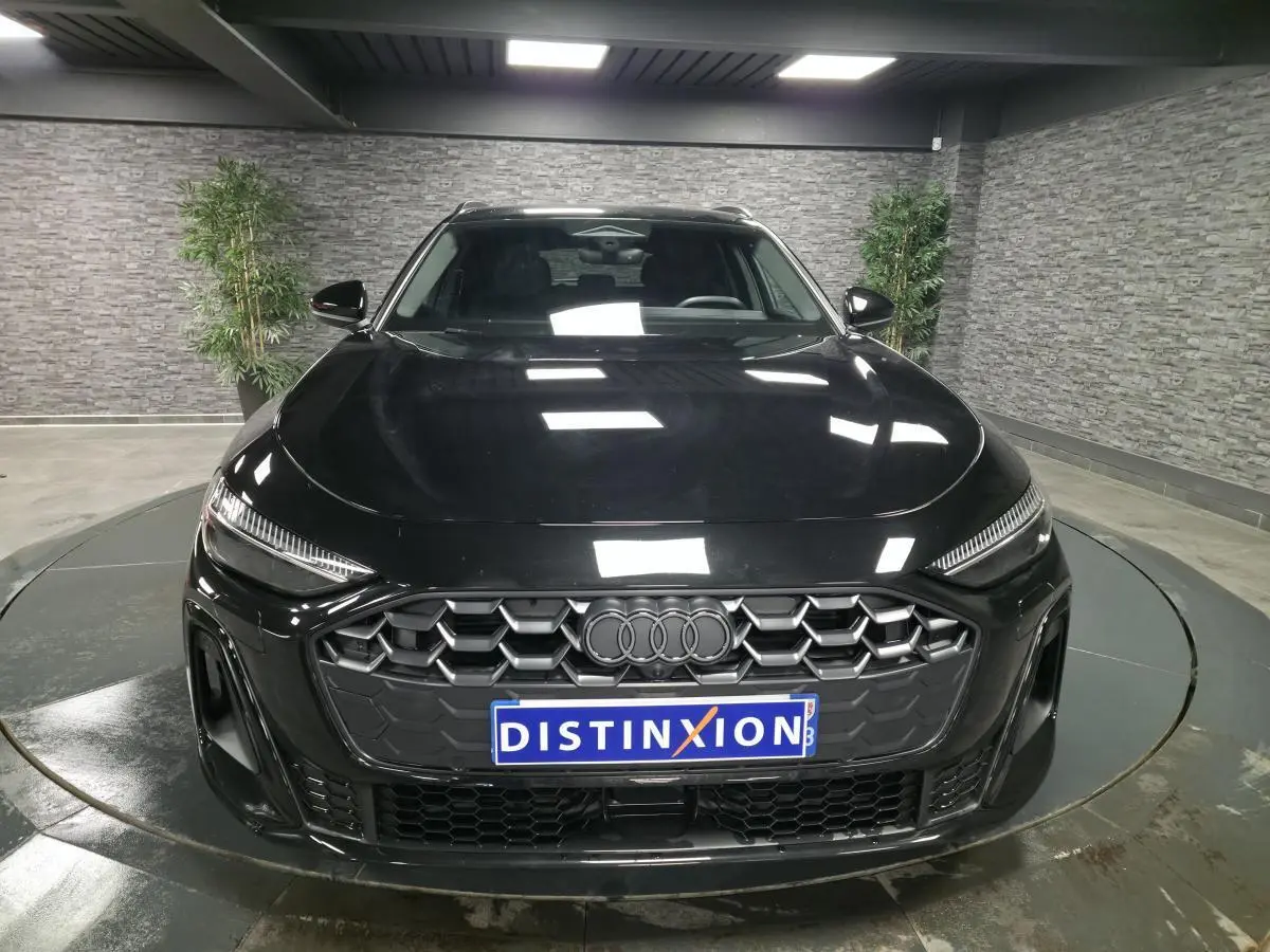 Vue avant d'une Audi A5 Avant noire 2025 avec calandre hexagonale et anneaux Audi gris anthracite.