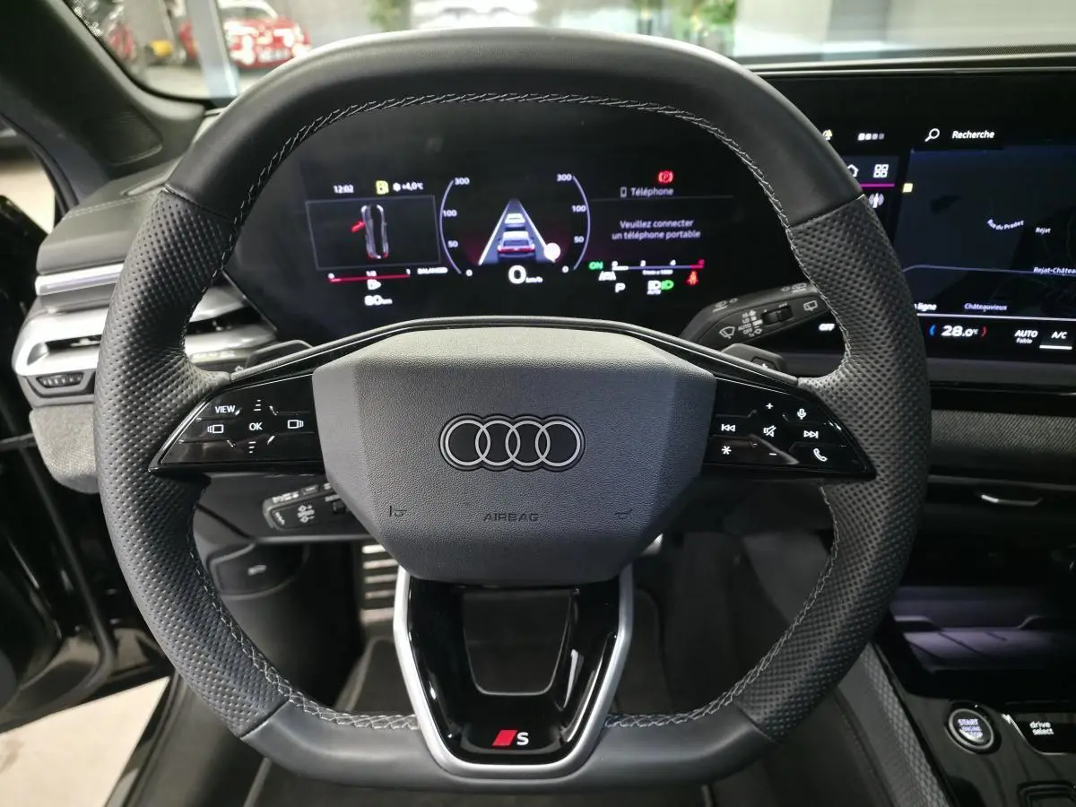 Vue rapprochée du volant sport en cuir noir avec logo Audi S et tableau de bord numérique d'une Audi A5 Avant 2025.