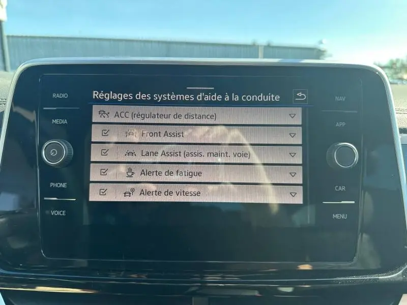 Écran tactile central du Volkswagen T-Roc noir nacré, affichant les réglages d’aides à la conduite.