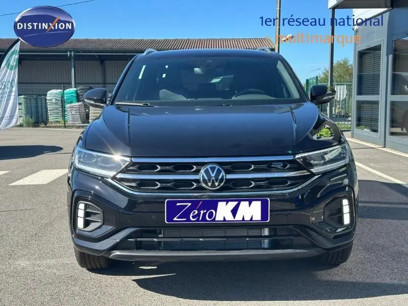 Vue avant frontale du Volkswagen T-Roc noir intense nacré avec calandre chromée et feux LED allumés.
