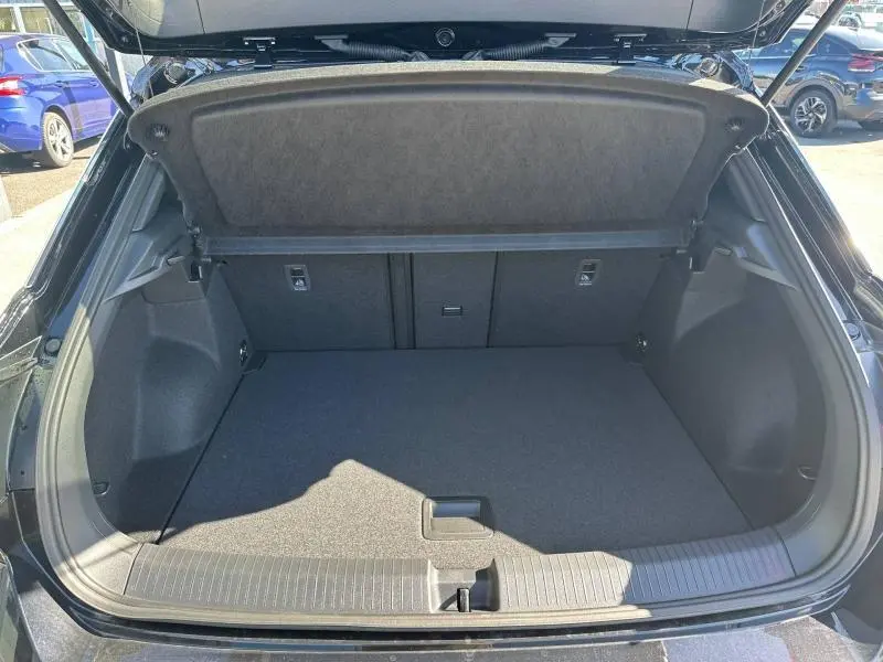 Coffre ouvert vu de l'arrière d'un Volkswagen T-Roc noir intense nacré, montrant un espace de chargement propre et spacieux.