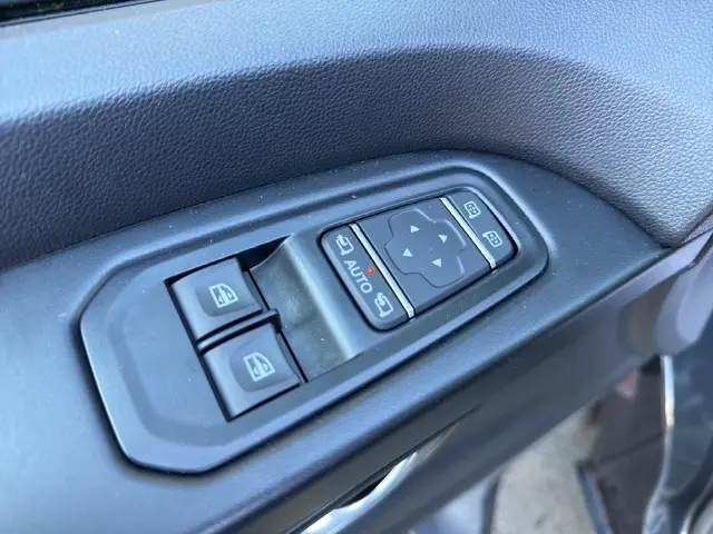 Gros plan sur les commandes électriques des vitres et des rétroviseurs côté conducteur d’un Nissan Primastar gris foncé.