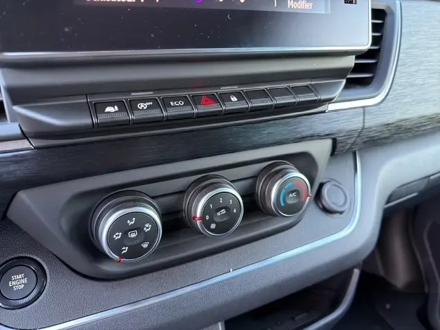 Gros plan sur les commandes de climatisation et boutons multifonctions du tableau de bord gris foncé du Nissan Primastar 2025.