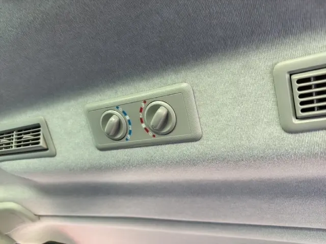 Détail du plafonnier gris clair avec commandes de climatisation et aérateurs dans un Nissan Primastar gris foncé.