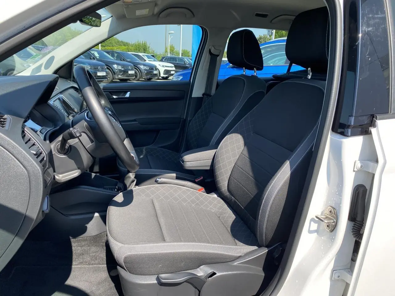 Intérieur côté conducteur d'une Skoda Fabia blanche 2021, sièges noirs satin avec motifs gris et volant multifonctions.