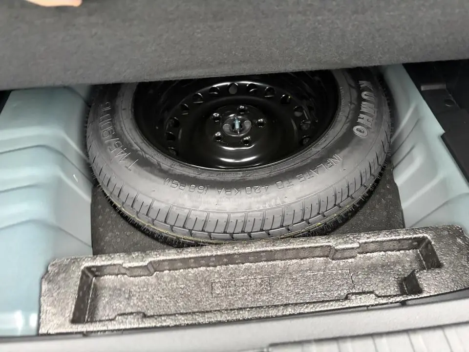 Vue du coffre ouvert montrant la roue de secours noire du Renault Arkana 2025, détail du rangement intérieur.