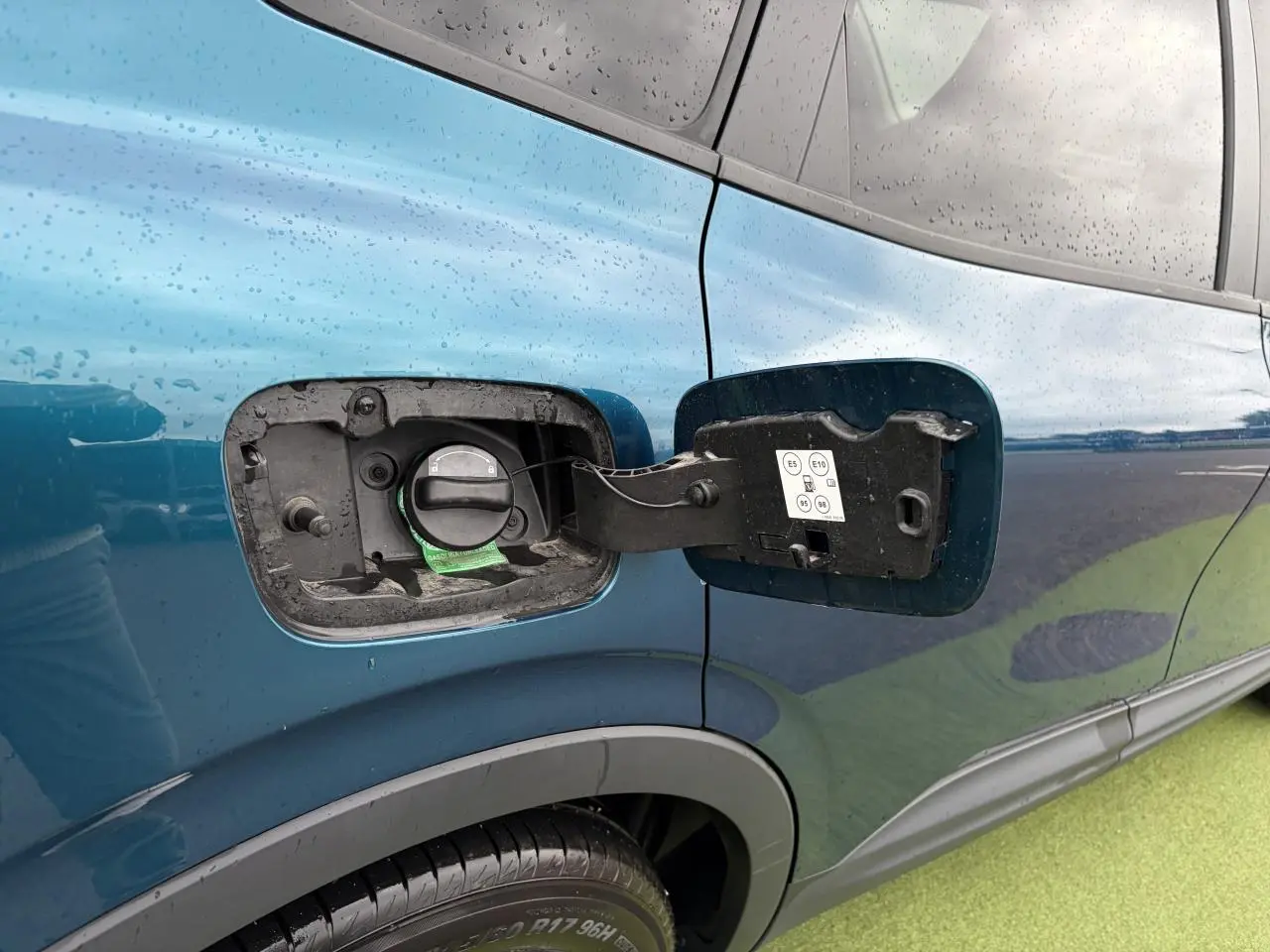 Vue rapprochée sur la trappe à carburant côté gauche d’un Renault Arkana bleu Zanzibar métallisé.