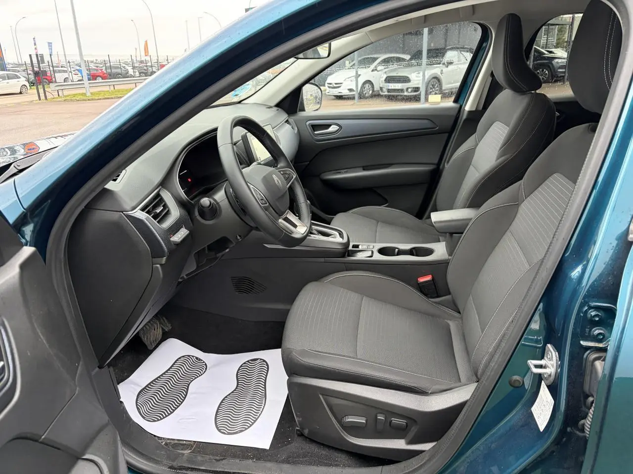 Vue intérieure côté conducteur de la Renault Arkana 2025 bleu Zanzibar, avec sièges gris et volant multifonction.