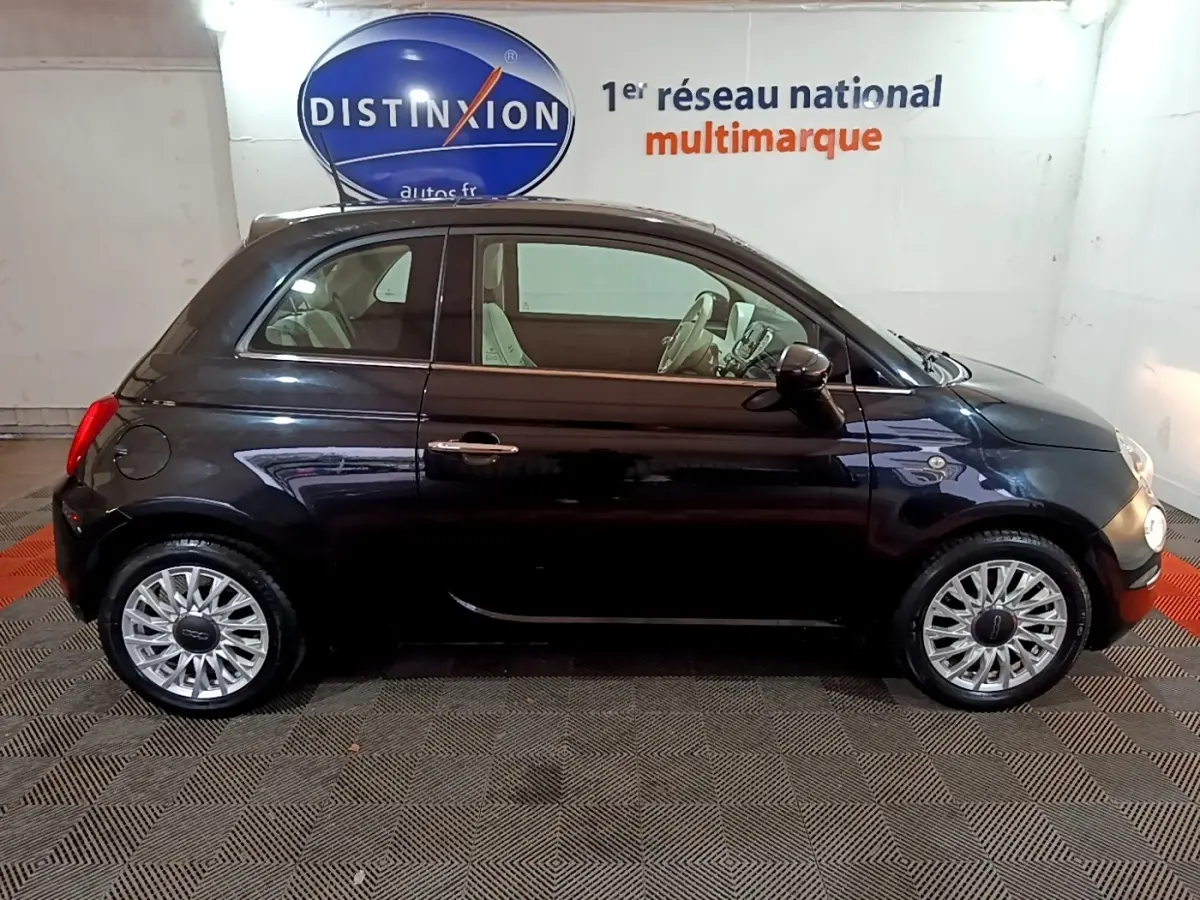 Profil droit d'une Fiat 500 noire 2019, avec jantes alliage et intérieur clair visible en showroom.