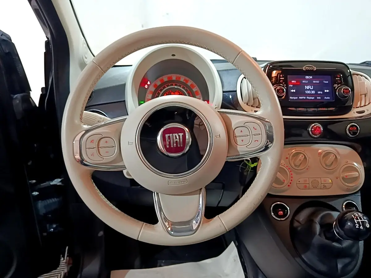 Vue intérieure centrée sur le volant beige de la Fiat 500 2019 avec tableau de bord et écran tactile noir.