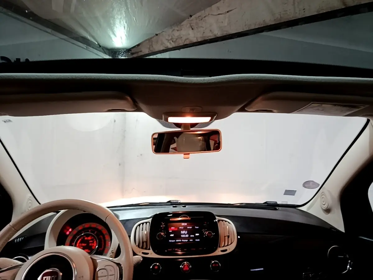 Vue intérieure avant du tableau de bord et volant beige de la FIAT 500 Lounge 2019 avec écran tactile central allumé.