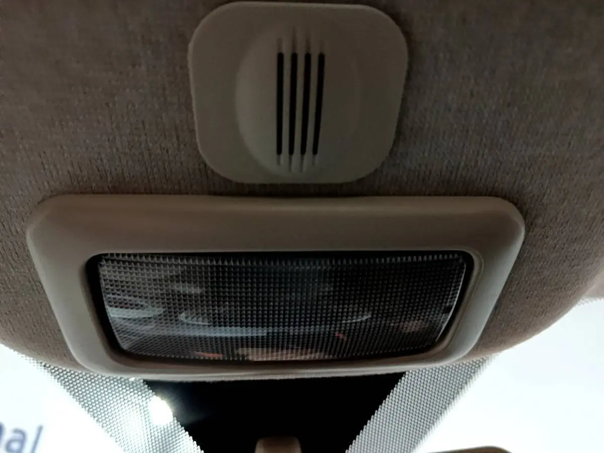 Gros plan sur la lumière intérieure et le plafonnier beige du toit d'une Fiat 500 noire vue de l'intérieur.