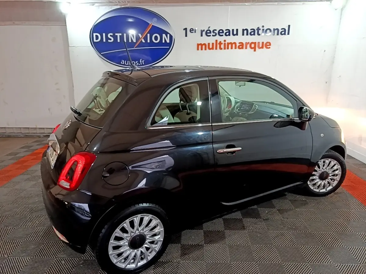Vue 3/4 arrière droite d'une FIAT 500 noire 2019 avec jantes alliage et intérieur beige visible en showroom.