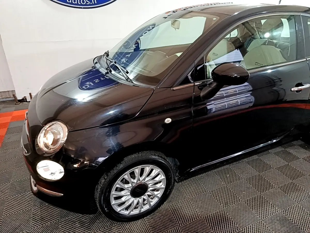 Vue 3/4 avant droit d'une FIAT 500 Lounge noire avec jantes alliage et intérieur clair visible.