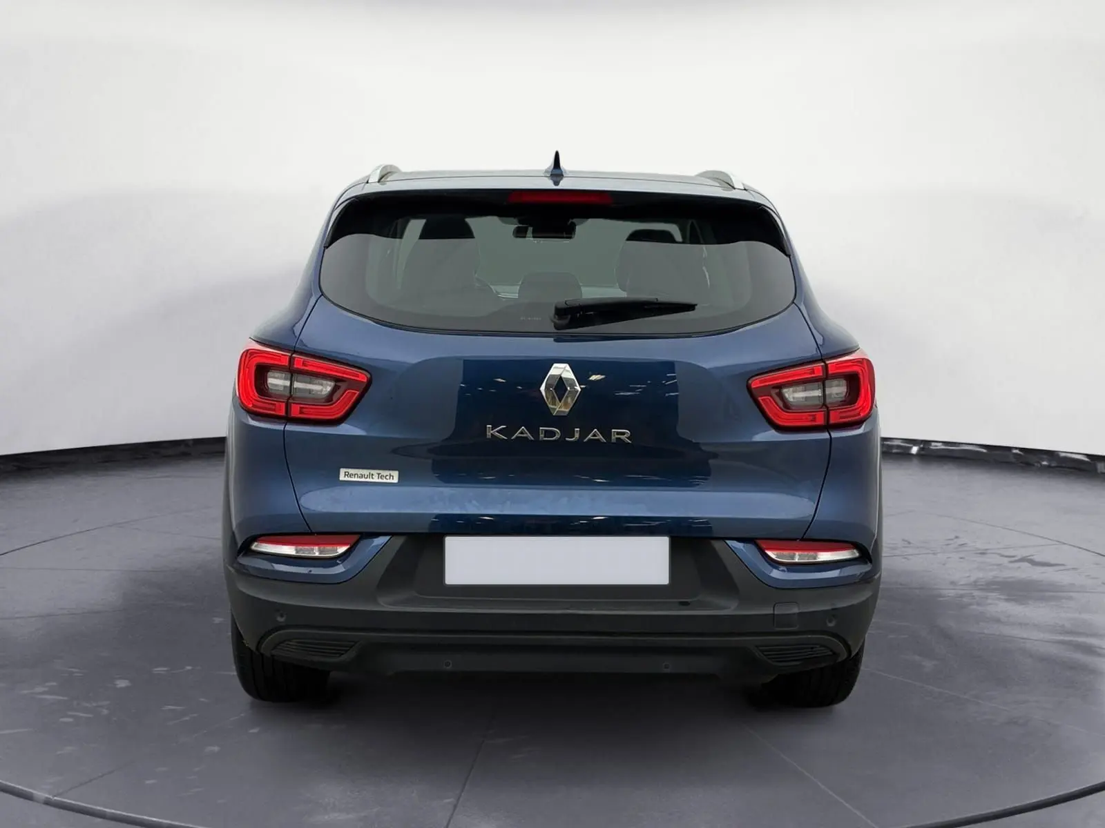 Vue 3/4 arrière droite d’un Renault Kadjar bleu cosmos 2020 garé sur un sol gravillonné en extérieur.