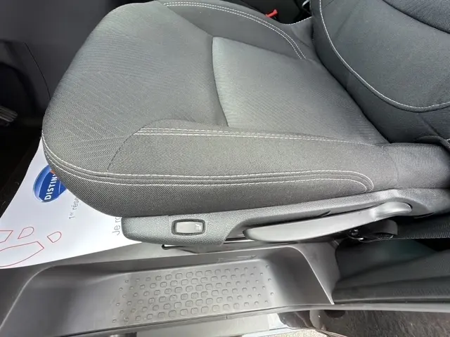 Gros plan sur le siège avant conducteur noir du Nissan Primastar 2025, montrant le réglage manuel et la moquette au sol.