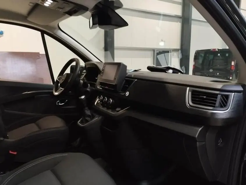 Vue intérieure côté conducteur du Nissan Primastar noir, avec tableau de bord moderne et écran tactile central.