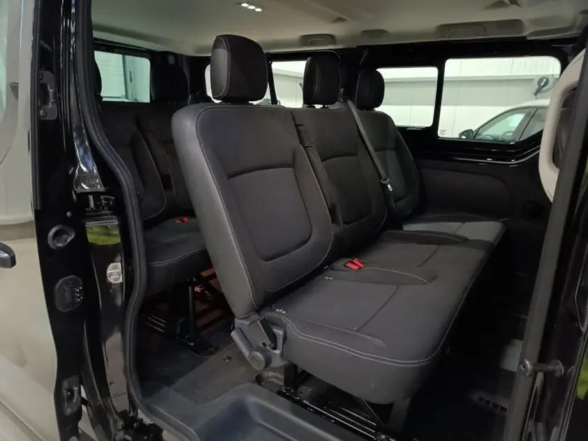 Vue intérieure côté droit du Nissan Primastar noir, montrant les sièges passagers en tissu avec ceintures de sécurité.