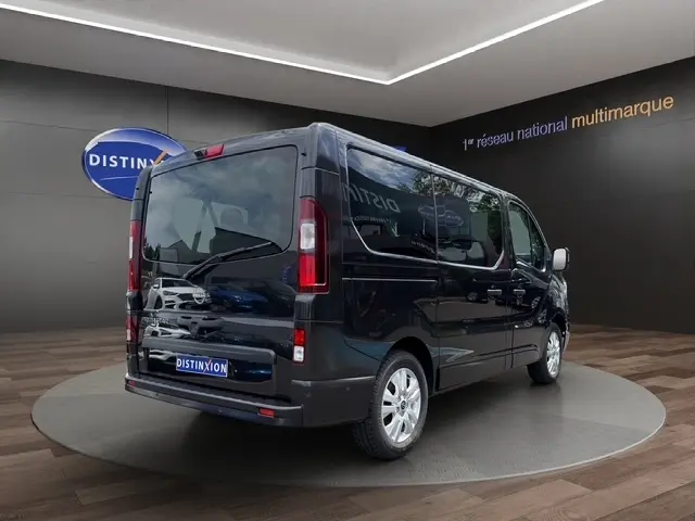 Vue 3/4 arrière droite d’un Nissan Primastar noir 2025 avec vitres teintées et jantes argentées en showroom.