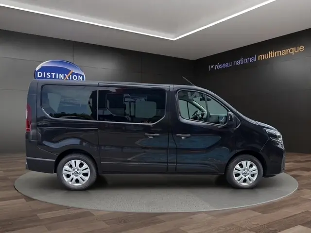 Vue latérale droite d’un Nissan Primastar noir 2025 avec portes latérales et jantes alliage, en intérieur showroom.