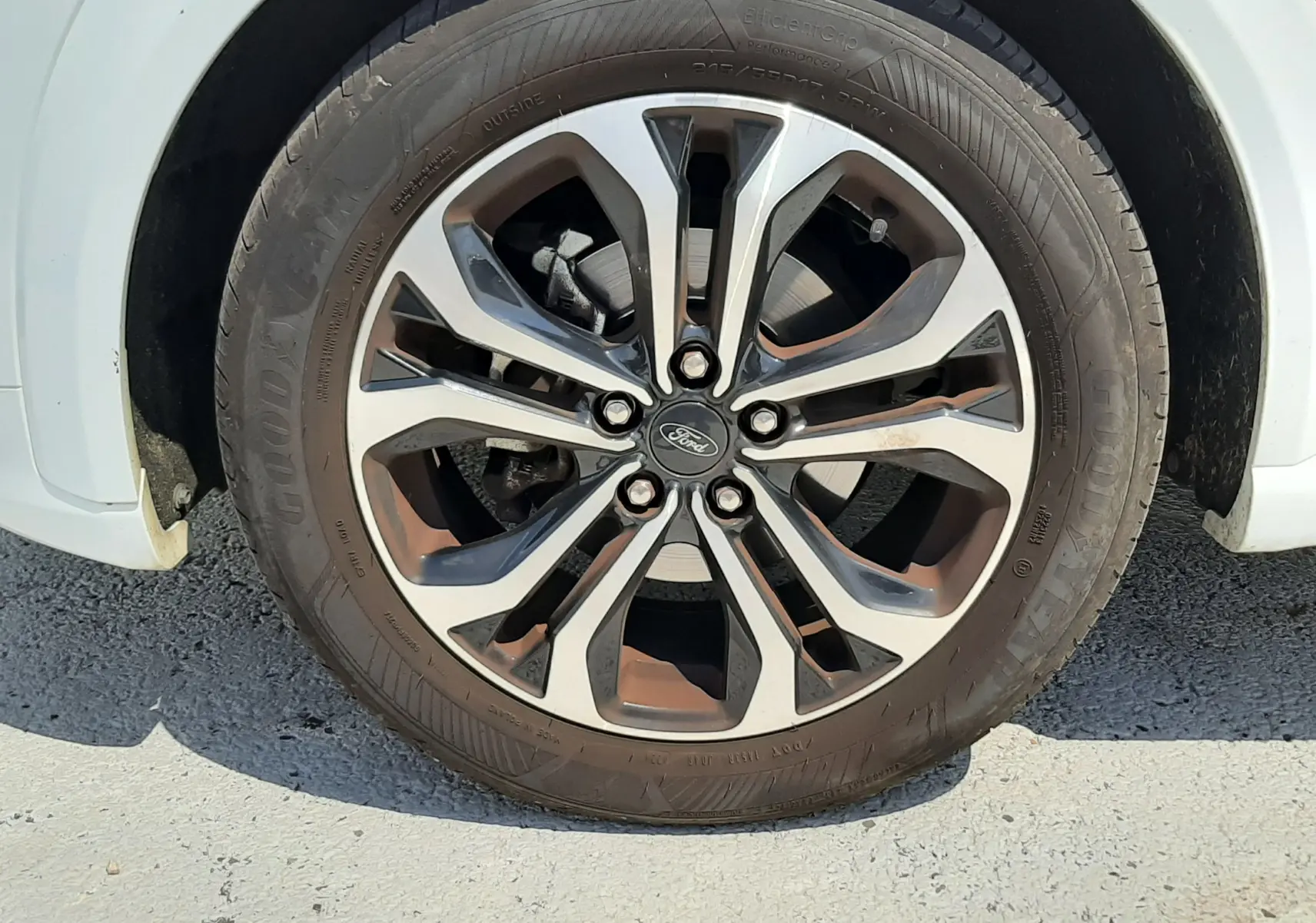 Gros plan sur la roue avant droite d'un Ford Puma blanc 2022 avec jante alliage bicolore et pneu Goodyear.