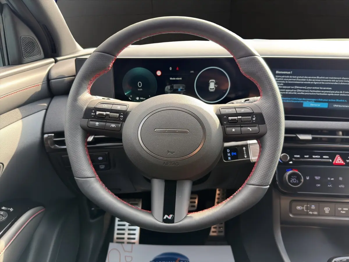 Vue intérieure centrée sur le volant sport cuir noir avec surpiqûres rouges du Hyundai Tucson 1.6 Hybrid N Line 2026.