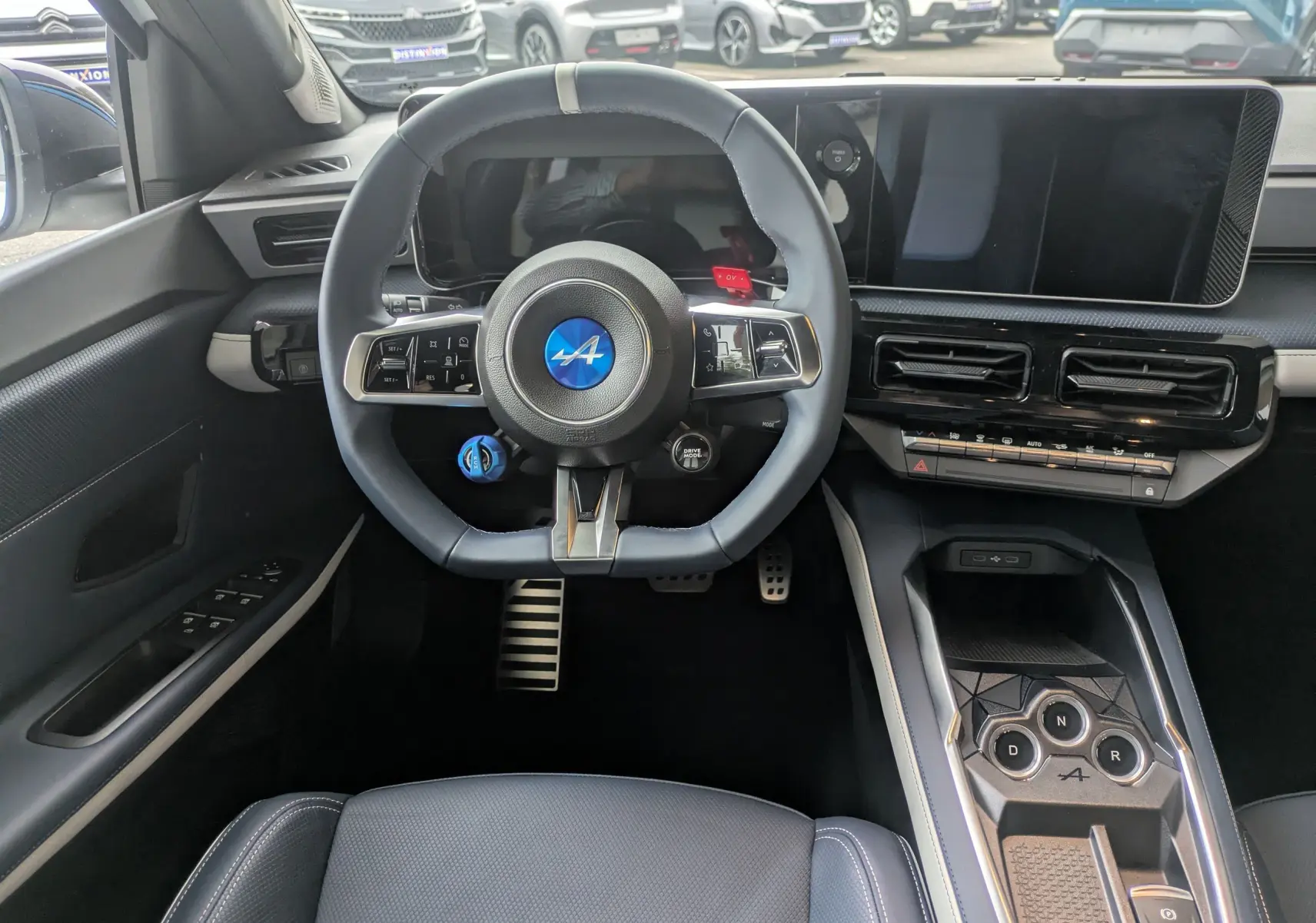 Vue intérieure centrée sur le volant bleu Alpine et la console centrale du tableau de bord de l'Alpine A290 220CH GTS.