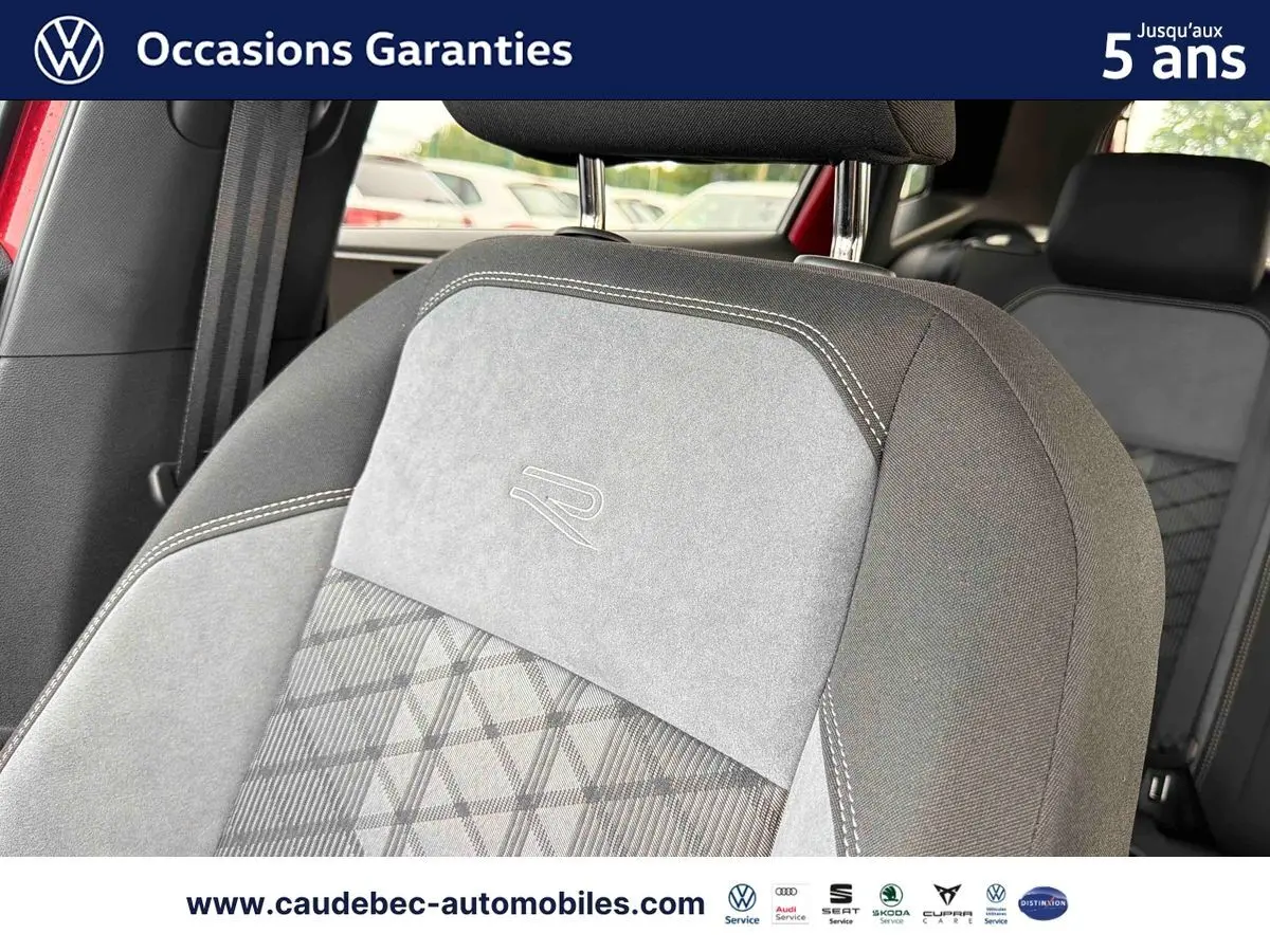 Détail du siège avant gris avec logo R brodé, intérieur de Volkswagen Polo rouge visible en arrière-plan.