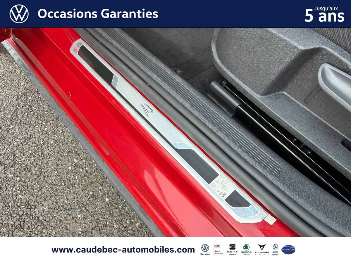 Gros plan sur la porte côté conducteur rouge d’une Volkswagen Polo avec seuil de porte R lumineux.
