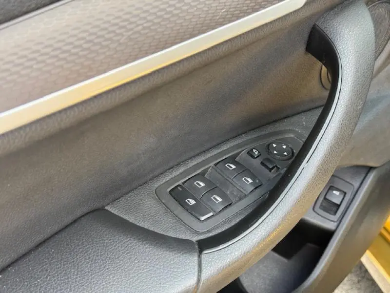 Gros plan sur la commande des vitres côté gauche de la porte intérieure noire du BMW X2 Galvanic Gold 2021 hybride rechargeable.