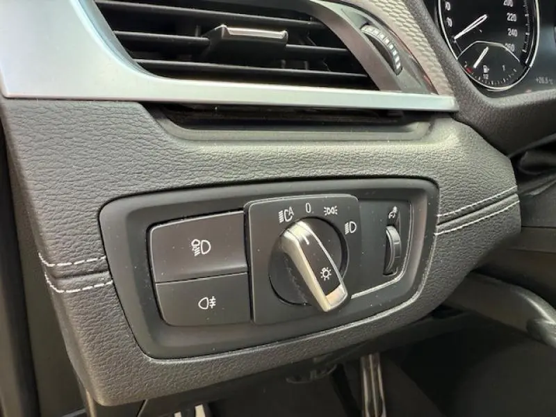 Gros plan sur le bouton de commande des phares dans l'habitacle d'un BMW X2 Galvanic Gold de 2021.