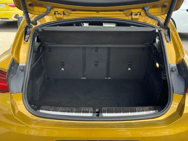 Coffre ouvert vu de l'arrière d'un BMW X2 xDrive25eA 2021 en Galvanic Gold métallisé, montrant l'espace de chargement vide.