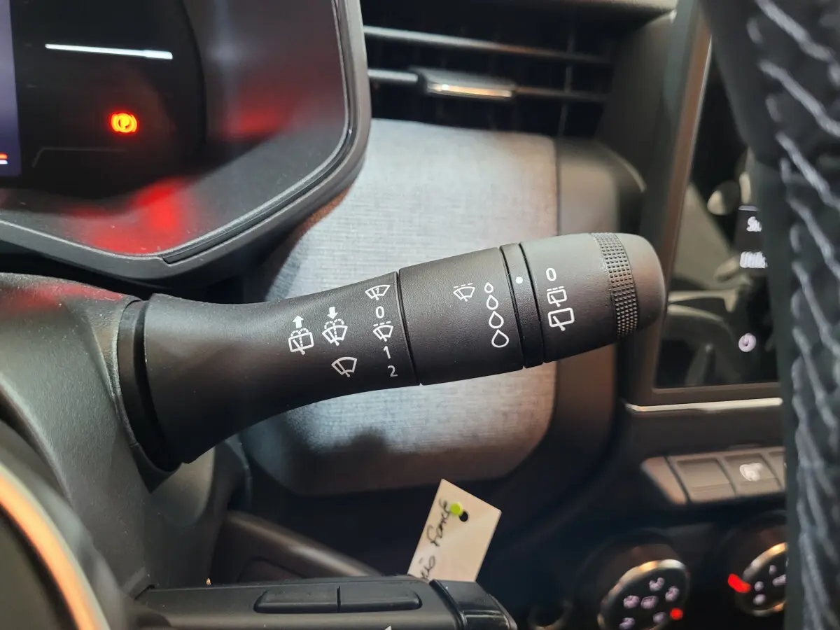 Gros plan sur la commande d'essuie-glaces à gauche du volant dans l'habitacle gris foncé d'une Renault Clio 2025.