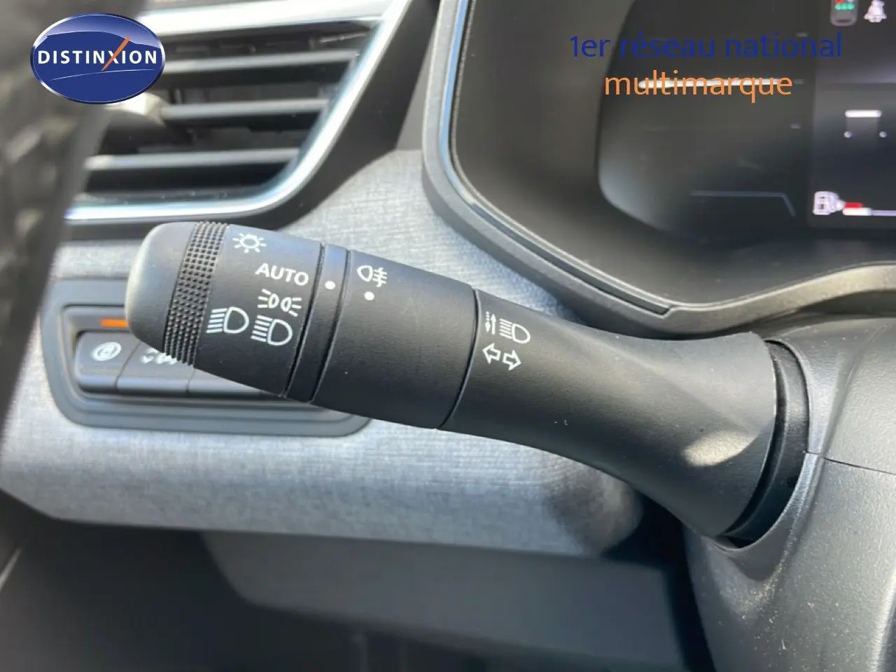 Gros plan sur la commande des phares et clignotants à gauche du volant dans l’habitacle gris d’une Renault Clio 2025.