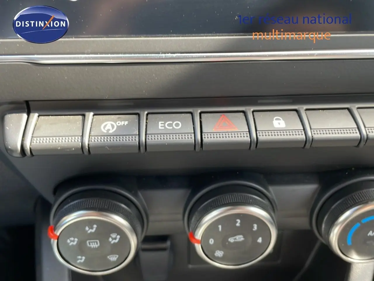 Gros plan sur les commandes de climatisation et boutons fonctionnels du tableau de bord d’une Renault Clio gris schiste.