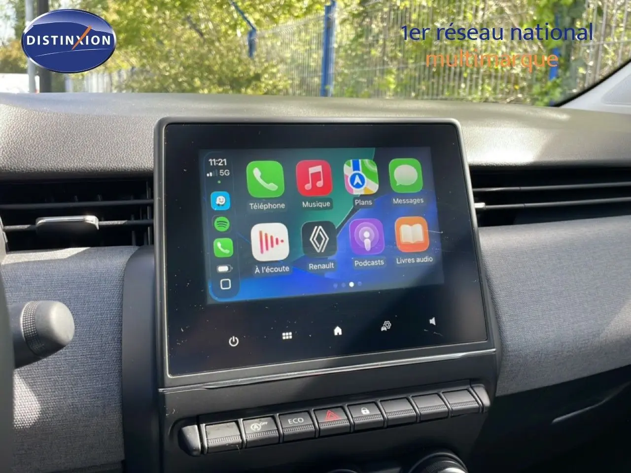 Écran tactile central de la Renault Clio 2025 affichant l'interface multimédia, entouré d'une planche de bord grise.