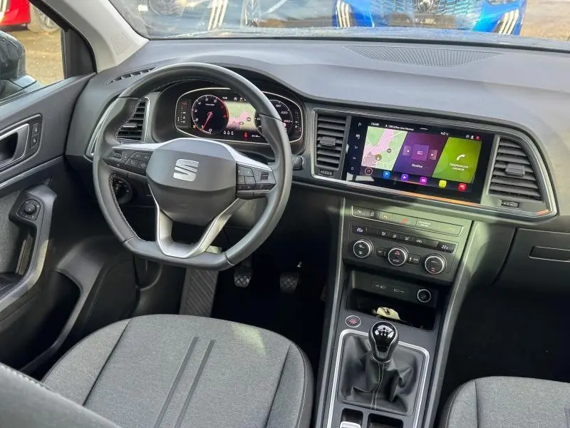 Vue intérieure côté conducteur du SEAT Ateca 2024 noir, avec volant cuir multifonction et écran tactile GPS.