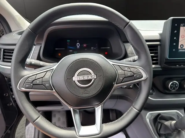 Vue rapprochée du volant noir en cuir synthétique d’un Nissan Primastar 2025 avec commandes multifonctions et tableau de bord numérique.