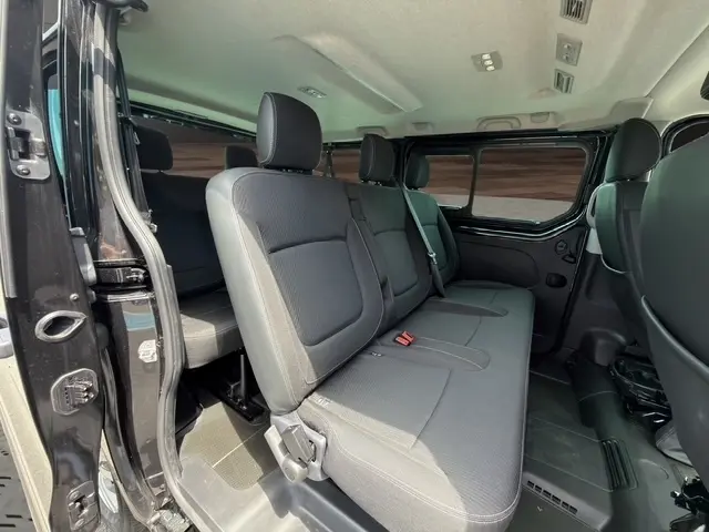 Vue intérieure côté droit du Nissan Primastar noir 2025, montrant la banquette arrière et la porte latérale ouverte.