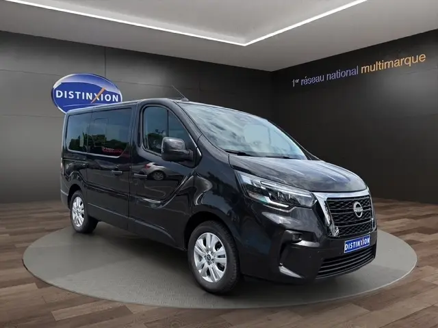 Vue 3/4 avant droite du Nissan Primastar noir avec calandre chromée et feux LED, sur fond showroom Distinxion.