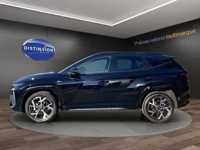 Vue latérale droite du Hyundai Tucson 1.6 Hybrid noir 2026 avec jantes alliage et spoiler de toit visible.