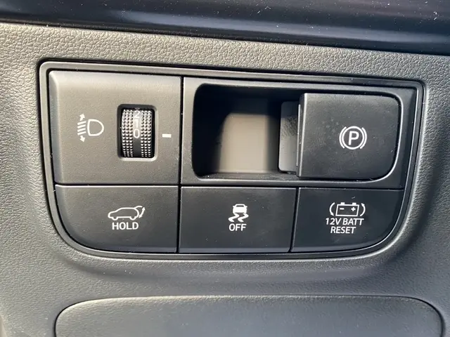 Gros plan sur les commandes intérieures du Hyundai Tucson 1.6 Hybrid N Line 2026, avec bouton de frein à main électrique et réglage phares.